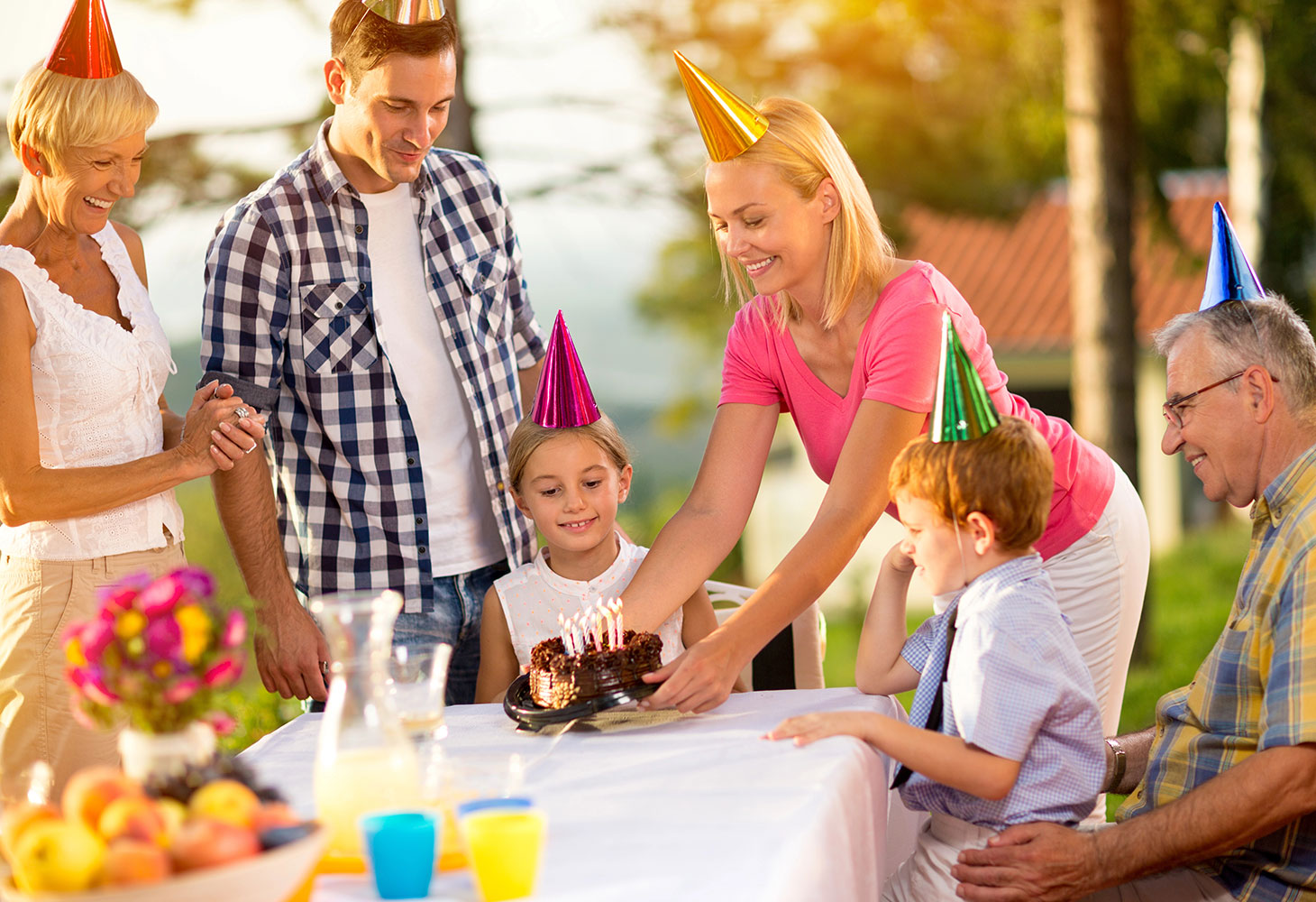 A family celebrating a child’s birthday at an outdoor party.