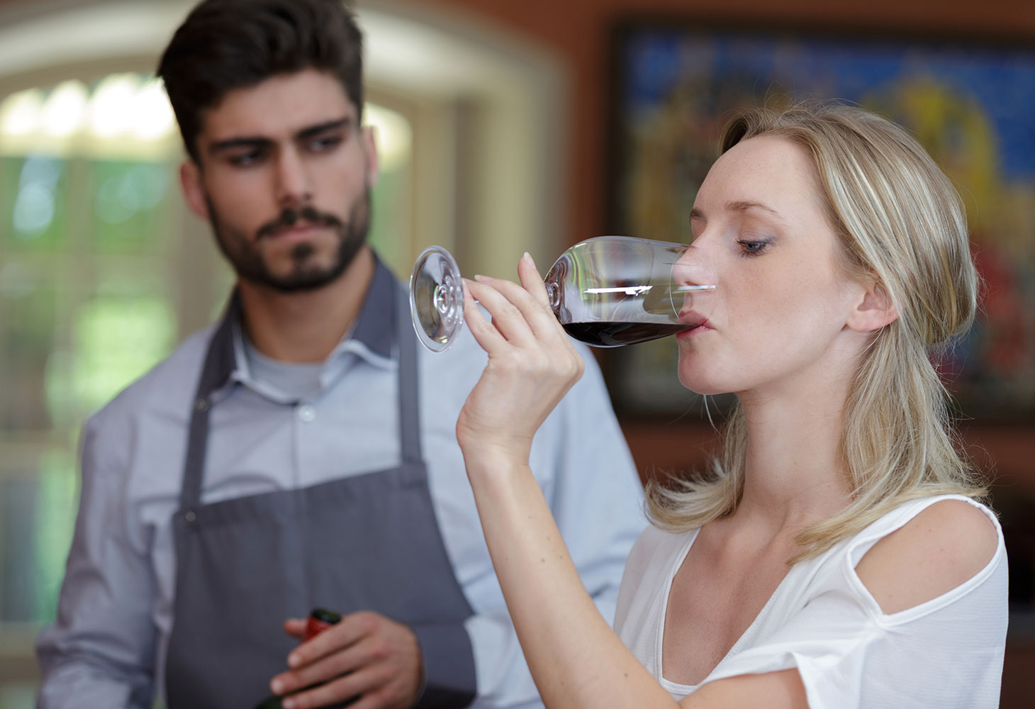 A woman participating in a wine tasting event led by a sommelier.