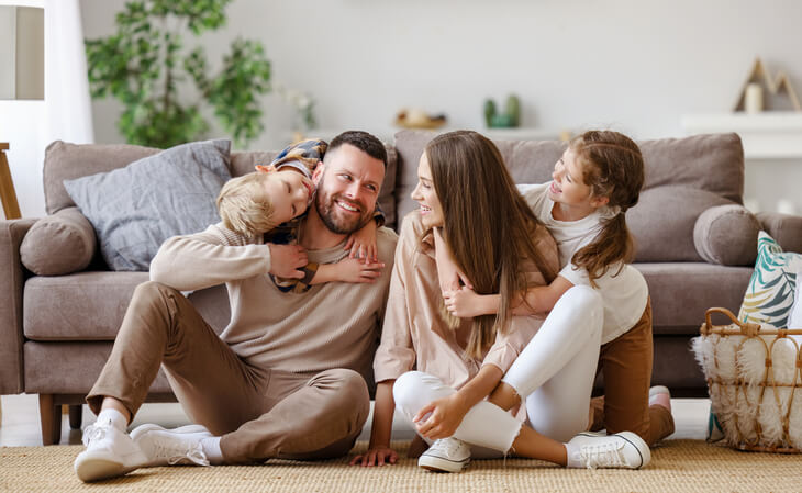 A young family—mom, dad, son, and daughter—spending time together in their living room.