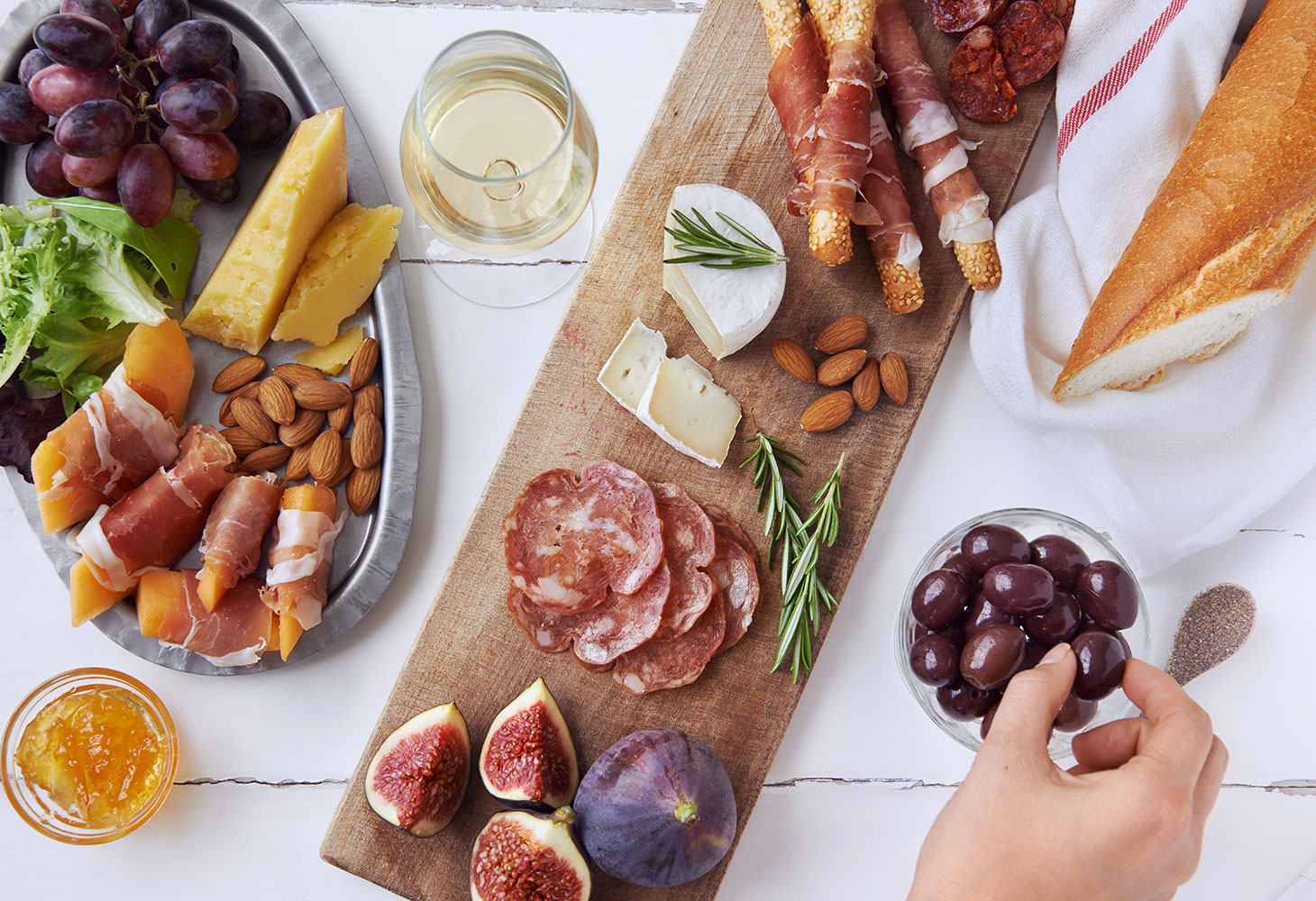charcuterie board of meats, cheeses, fruits, and nuts with a glass of wine.